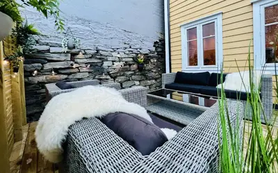 a patio with a couch and a stone wall at Eksklusiv leilighet sentralt i Bergen in Bergen