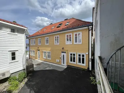 a yellow house with a red roof next to a building at Eksklusiv leilighet sentralt i Bergen in Bergen