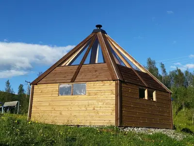 a small cabin with a pitched roof on a field at Hessdalen Ufocamp in Vårhus