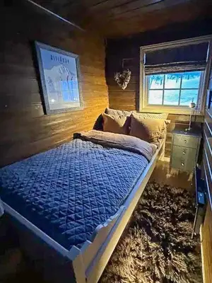 a bedroom with a bed with a blue comforter and a window at Lovely Family Cabin Near Ski Stadium In Beitostølen in Beitostøl