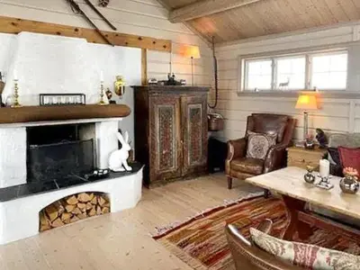 a living room with a fireplace and a chair at Lovely Family Cabin Near Ski Stadium In Beitostølen in Beitostøl