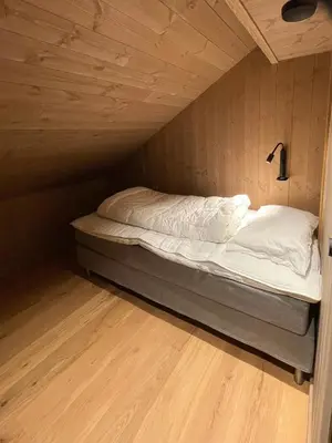 a small bed in a room with a wooden floor at Lovely Cabin With Hot Tub Near Syningtoppen in Torpo