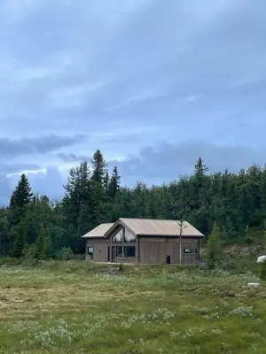 a house in a field with trees in the background at Lovely Cabin With Hot Tub Near Syningtoppen in Torpo