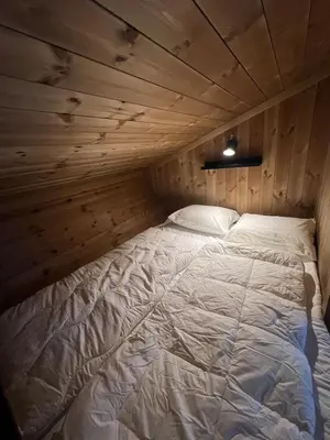 a bed in a room with a wooden wall at Charming and modern ski-in ski-out cottage in Hemsedal