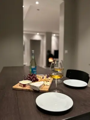 a wooden table with a glass of wine and cheese at Koselig sentrumsleilighet - Nær Bryggen in Bergen