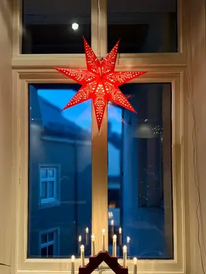 a red star decoration in a window with candles at Koselig sentrumsleilighet - Nær Bryggen in Bergen
