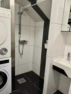 a small bathroom with a shower and a washing machine at Koselig sentrumsleilighet - Nær Bryggen in Bergen