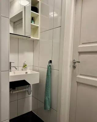 a white bathroom with a sink and a door at Koselig sentrumsleilighet - Nær Bryggen in Bergen
