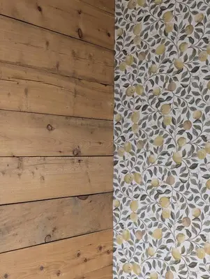 a bed with a floral pattern on a wooden wall at Lundenhuset 1917 - historic house in the heart of Ulsteinvik in Ulstein