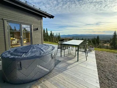 a deck with a hot tub and a table and chairs at Modern Cabin With Ski-Inout Near Birken Trails in Rena