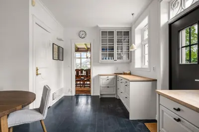 a kitchen with white cabinets and a table and a clock at Elegant Historic Villa - Stunning Views in Bergen