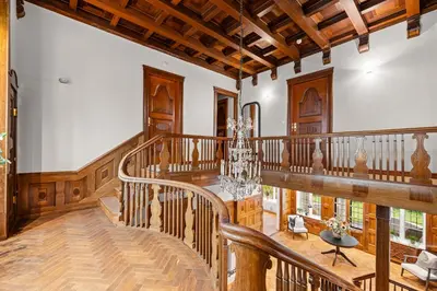 a large room with a wooden staircase with a chandelier at Elegant Historic Villa - Stunning Views in Bergen