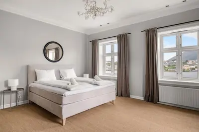 a white bedroom with a large bed and windows at Elegant Historic Villa - Stunning Views in Bergen