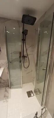 a shower with a glass door in a bathroom at Rooms in easy accessible new apartment near Stave church in Bergen