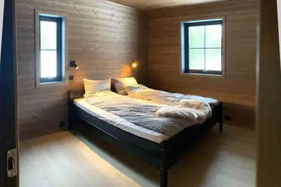 a bed in a room with two windows at Cabin With Ski Inout Near Stryn Alpine Resort in Stryn
