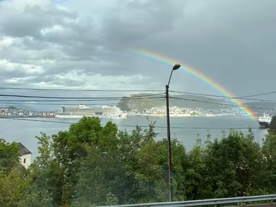 a rainbow over a body of water with a cruise ship at Alesund apartment fantastic view in Ålesund