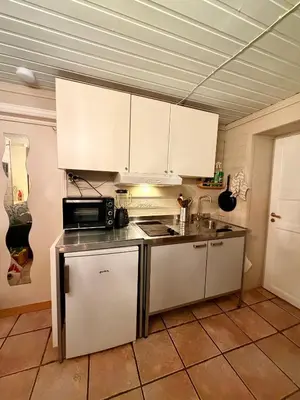 a kitchen with white cabinets and a sink and a microwave at Cozy little apartment at the back of Bryggen in Bergen
