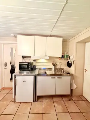 a kitchen with white cabinets and a sink at Cozy little apartment at the back of Bryggen in Bergen