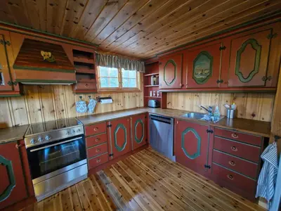 a kitchen with red cabinets and a sink and a stove at Fjellvang in Haglebu