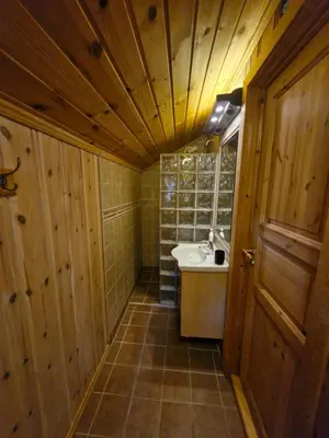 a bathroom with wooden walls and a sink and a mirror at Fjellvang in Haglebu