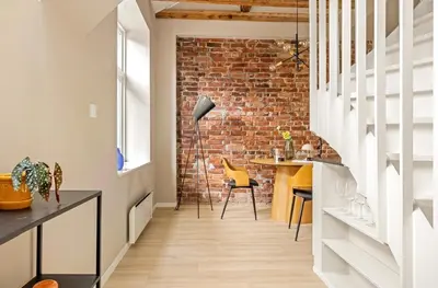 a room with a brick wall and a table and chairs at Koselig bygårdsleilighet i Bergen sentrum in Bergen