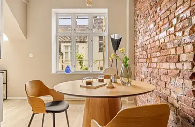 a dining room with a table and a brick wall at Koselig bygårdsleilighet i Bergen sentrum in Bergen