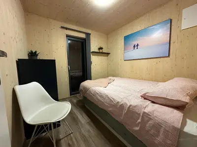 a bedroom with a bed and a white chair at Unique Nature Hideaway Close to Norefjell