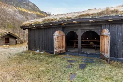 a barn with a grass roof with a bench inside at Jørundgard Vikingcamp in Sel