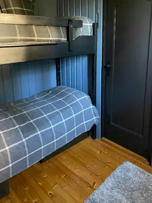 a bunk bed with a blue plaid blanket next to a door at Cabin With Ski Inout Near Gribbe, Valdres in Tisleidalen