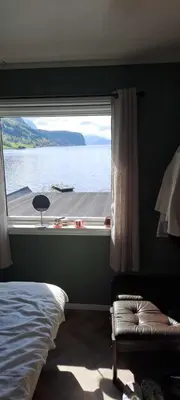 a bedroom with a window with a view of the water at Grodås Lake View Apartment in Hornindal