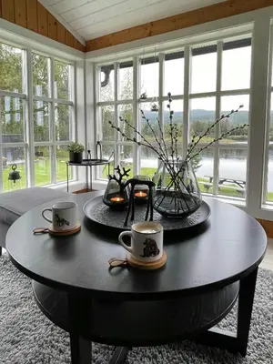 a coffee table with two cups and a vase on it at Modern Cottage With River Frontage Near Opphus in Rena