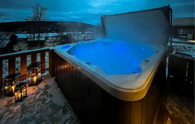 a jacuzzi tub on a balcony at night at Amazing Home In Røn With Sauna in Ron