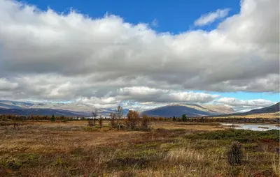 a field with mountains in the background with a cloudy sky at Amazing Home In Røn With Sauna in Ron