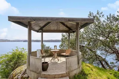 a gazebo with a table and chairs on a hill next to water at RVH29 - Fjord Hideaway Villa in Veland