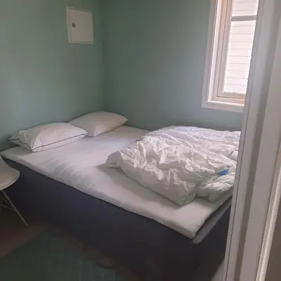 a bed with white sheets and pillows on it at Liten leilighet in Lii