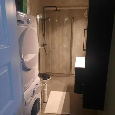 a bathroom with a shower and a washing machine at Liten leilighet in Lii