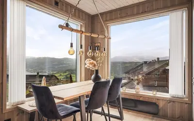 a dining room with a table and chairs and a large window at Exclusive and Uniqe Apartment - Ski in ski out! in Vossevangen