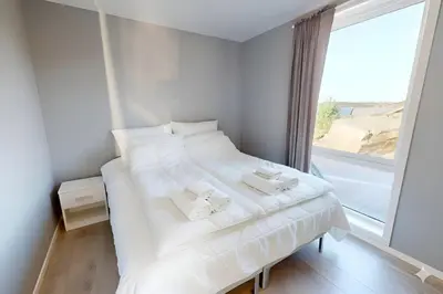 a white bed in a room with a large window at Ocean view and jacuzzi in Forland