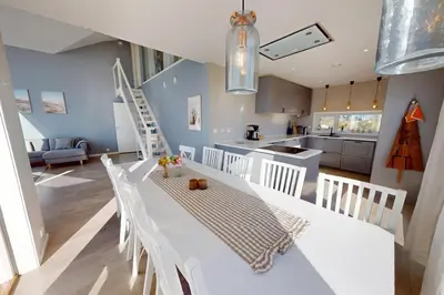 a kitchen and dining room with a white table and chairs at Ocean view and jacuzzi in Forland