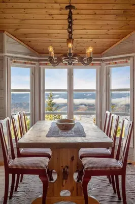 a dining room with a table and chairs and windows at Bekkeblom, family cabin with extension in Hafjell in Hafjell