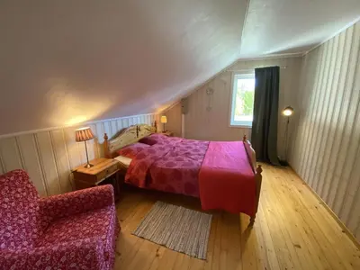 a bedroom with a bed and a chair and a window at A Cozy Nordic Home in Ålset