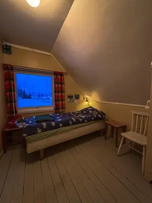 a bedroom with a bed and a window and a chair at Charming Norwegian Cottage in Lyngen