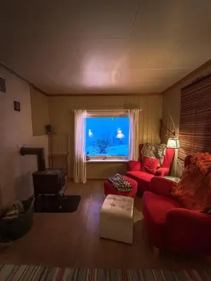a living room with a red couch and a window at Charming Norwegian Cottage in Lyngen