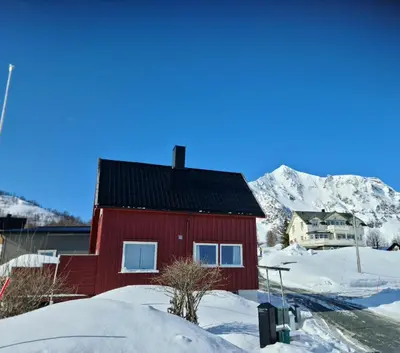 a red house in the snow with mountains in the background at Charming Norwegian Cottage in Lyngen