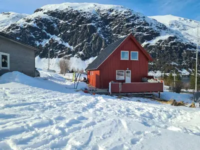a red house with a bench in the snow at Charming Norwegian Cottage in Lyngen