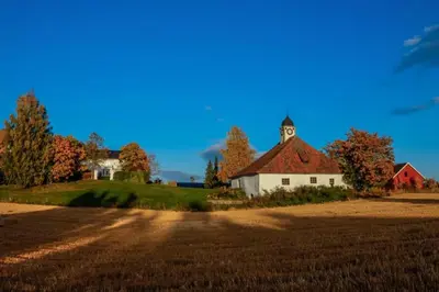 a house on a hill with a field and a church at Torshov Gård, Viking grounds in Hamar