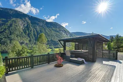 a wooden deck with a gazebo with mountains in the background at Luxury cabin with amazing views in Stryn
