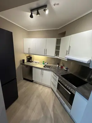 a kitchen with white cabinets and stainless steel appliances at Bright and modern city center apartment in Ålesund