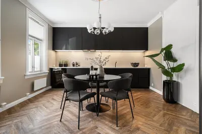 a kitchen with black cabinets and a table and chairs at Classic apartment with good standard in the city center in Trondheim
