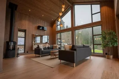 a living room with two couches and large windows at Luxury cabin, Wellness and view over the Tyrifjord in Vikersund
